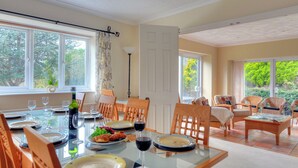 A dining area with a table set for four, chairs, and a view of the outdoors. - Manor Lodge (Bridport)