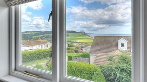 A window with a view of a rural landscape, including houses and greenery. - Pendower (Bridport)