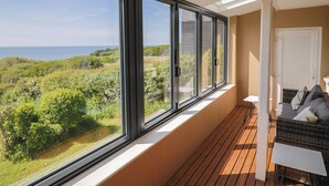 Un balcone con ampie finestre che si affaccia su un paesaggio rigoglioso e il mare.