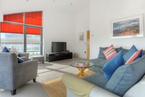 Un salon moderne avec un canapé gris, une table basse et un téléviseur.