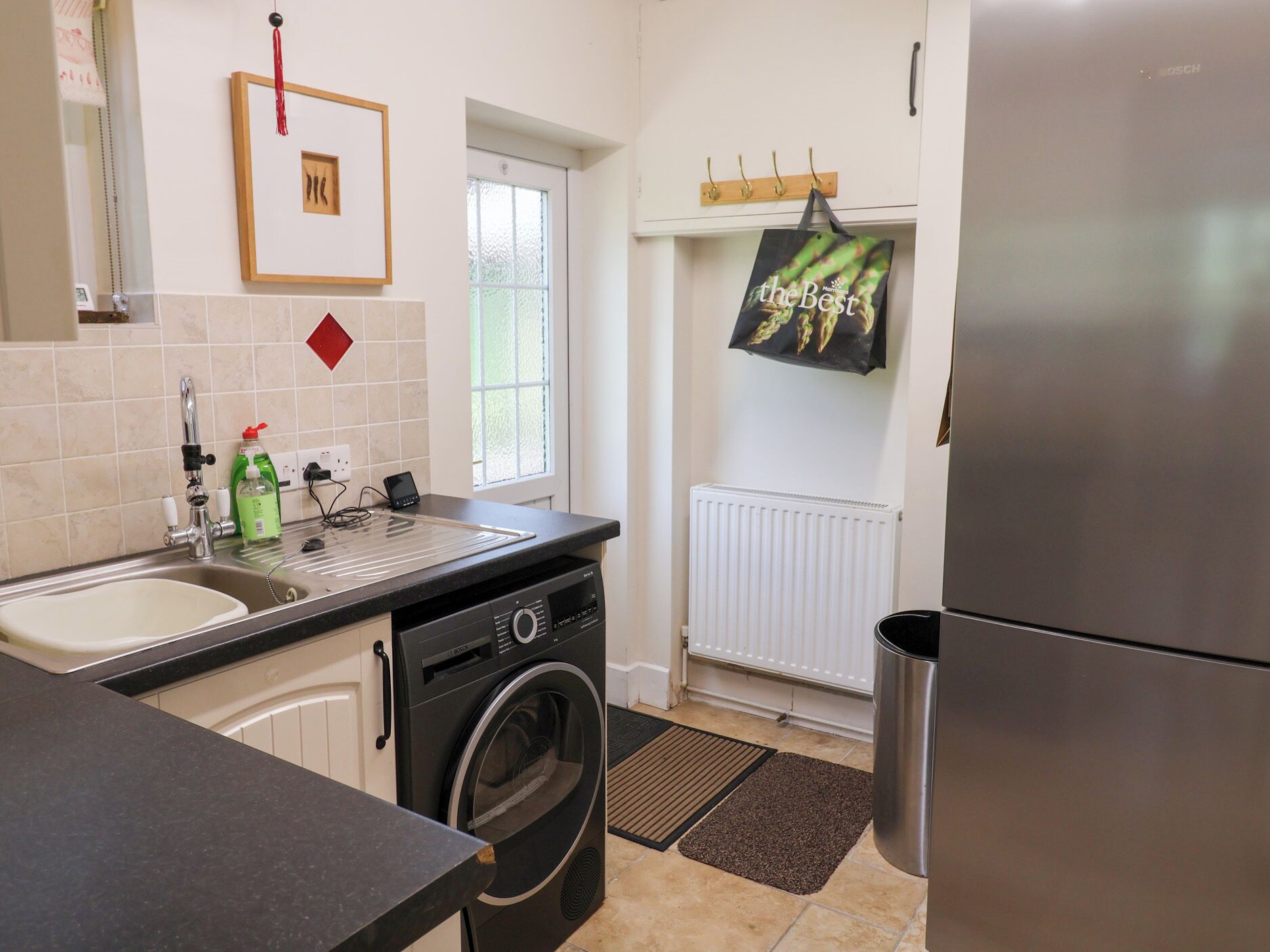 A modern kitchen with a built-in washing machine, a refrigerator, and a window with a view.