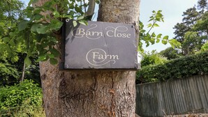 Een bord aan een boom met de tekst 'Barn Close Farm'.
