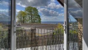 Varanda com vista para o mar, uma árvore e um edifício do outro lado da água.