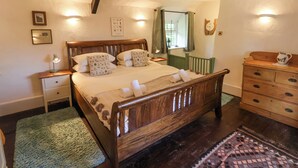 Quarto bem arrumado com cama de madeira, mesas de cabeceira, cômoda e janela com cortinas.