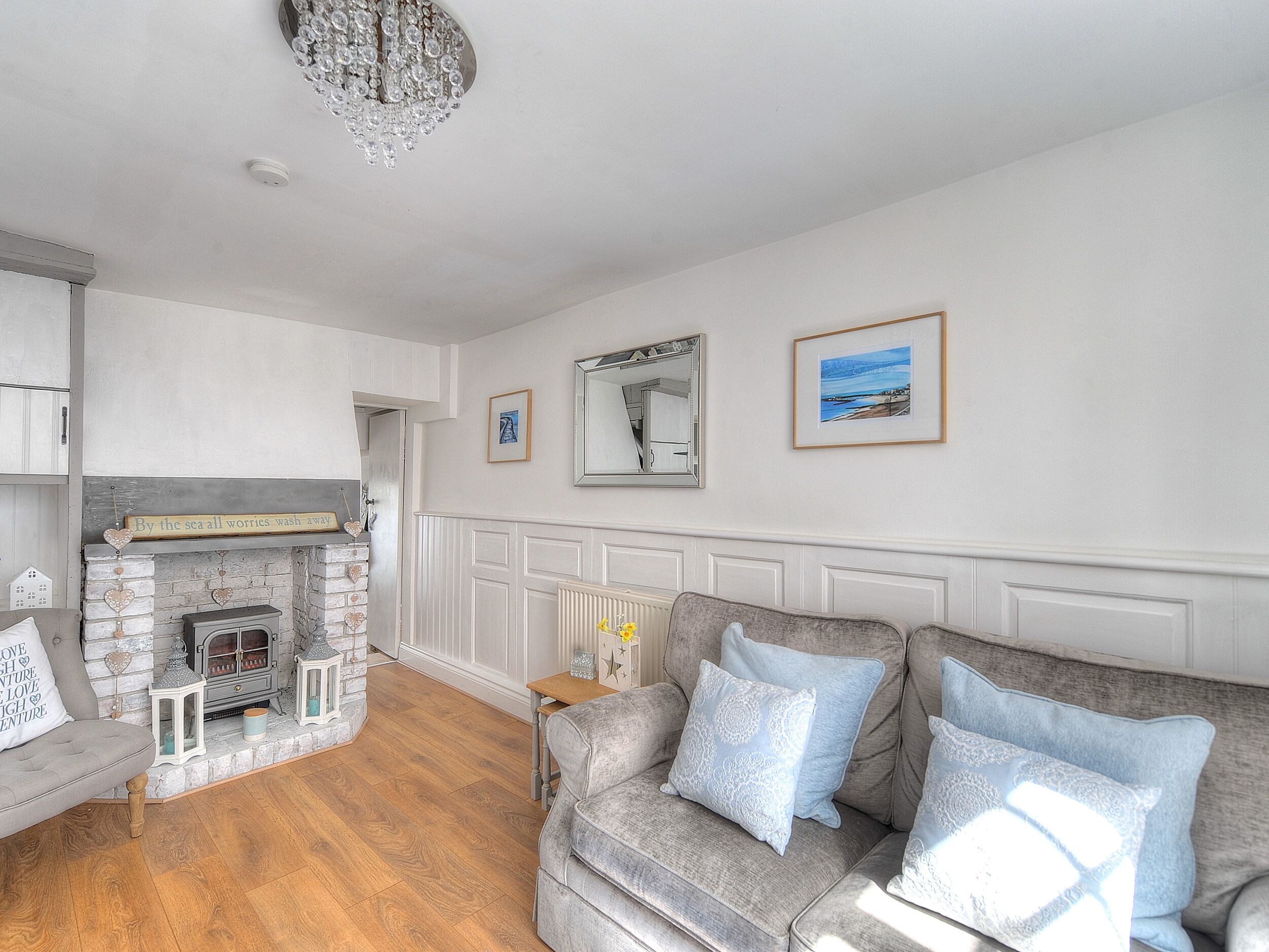 A living room with a fireplace, a sofa, a mirror, and framed pictures on the wall.