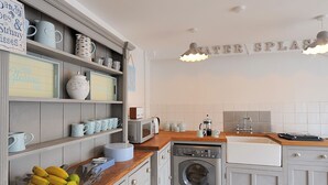 Une cuisine équipée d’un lave-linge, d’un évier et d’un plan de travail en bois.