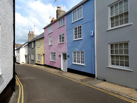 Una calle estrecha flanqueada por casas coloridas, cada una con estilos arquitectónicos únicos y diseños de ventanas diferentes.