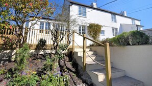A two-story white house with a wooden staircase leading to the upper floor. - Hillside Cottage (Lyme Regis)