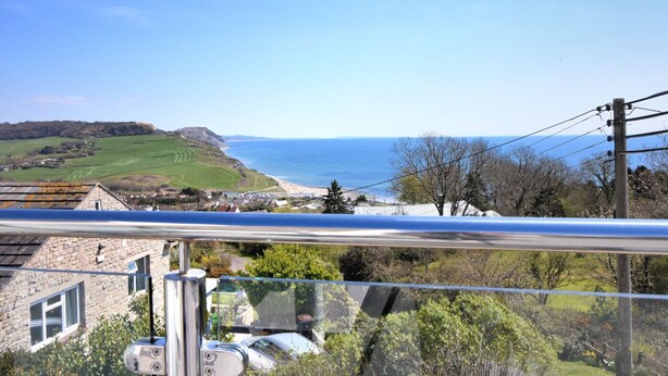 Blick auf die Küste mit blauem Himmel, einem Strand und einem Steinhaus im Vordergrund.