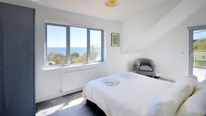 Ein Schlafzimmer mit großem Fenster, einem Bett, einem Sessel und einer Heizung.