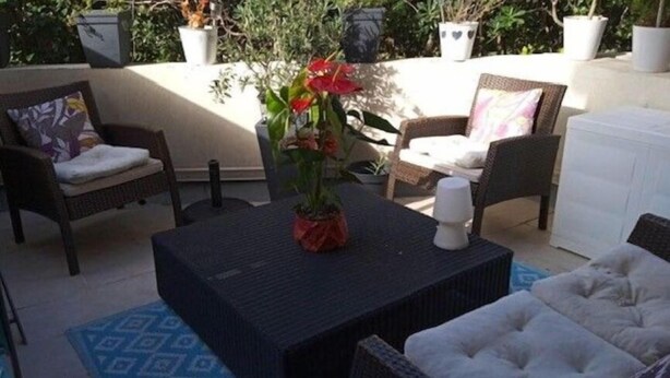 A patio area with wicker furniture, a table with a vase of flowers, and potted plants. - In residence 34m² sleeps 4 with pool on Capbreton harbour (Capbreton)