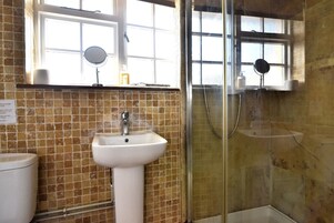 Un baño con lavamanos, espejo y zona de ducha.