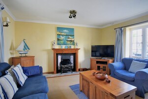Una sala de estar con chimenea, televisor y sofá.