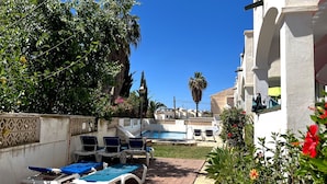 A poolside area with lounge chairs and a small pool, surrounded by greenery and a building with a white facade. - Nerja Paradise Rentals - Apartment El Califa 3 (Nerja)