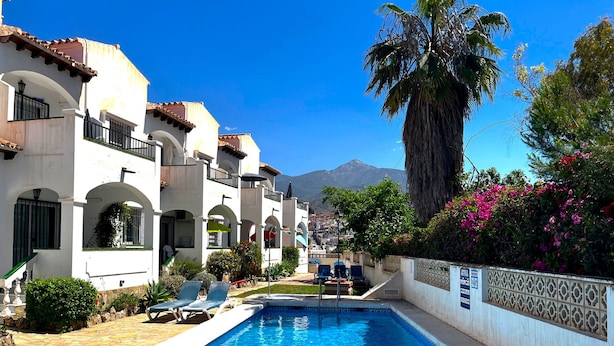 A swimming pool with lounge chairs, a palm tree, and a mountain in the background. - Nerja Paradise Rentals - Apartment El Califa 3 (Nerja)