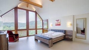 A bedroom with a sloped ceiling, large windows, a bed, a chair, and a desk. - Villa Golf (Karlovy Vary)