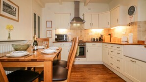A kitchen with white cabinets, a wooden dining table, and chairs.