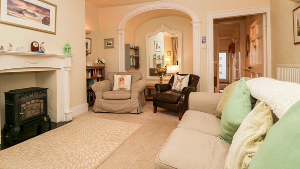 A living room with a fireplace, two armchairs, a sofa, and a bookshelf.