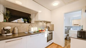 Een moderne keuken met witte kasten, een roestvrijstalen fornuis en een inbouwoven.