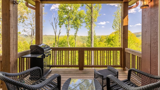 A covered outdoor area with a grill, wicker chairs, and a table. - Bear Crossing at Echota - Long mountain views, indoor/outdoor pool access, hiking trails, gym (Banner Elk)