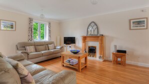 A living room with a sofa, a coffee table, a fireplace, and a television. - 1 Woodroffe Meadow (Lyme Regis)