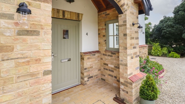 Un bâtiment en pierre avec une porte verte, une petite fenêtre et le chiffre « 4 » peint sur le mur.