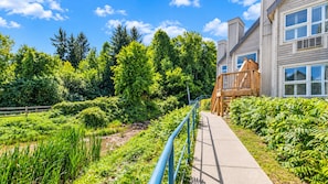A pathway leading to a building with a wooden deck and a clear sky. - Newly Renovated Ski-In Studio: Hot Tubs, Pool, Tennis, Walk or Ski to Slopes (Blue Mountains)
