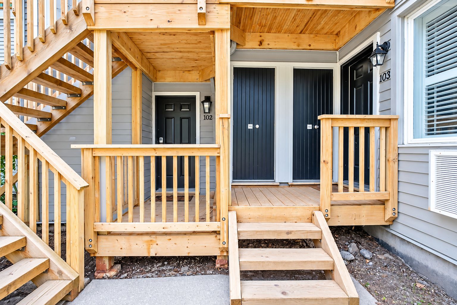 A wooden staircase leading to a porch with a railing, a front door, and a mailbox.