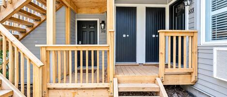 A wooden staircase leading to a porch with a railing, a front door, and a mailbox.