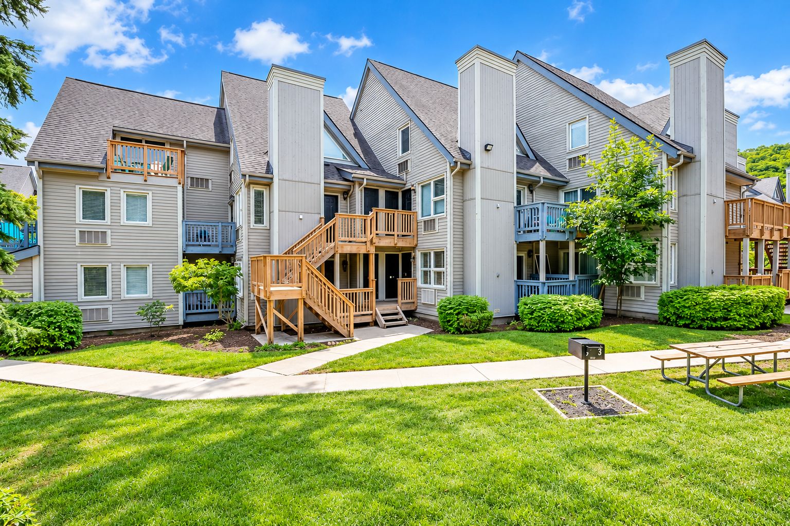 A multi-story residential building with a central staircase, balconies, and a well-maintained lawn.