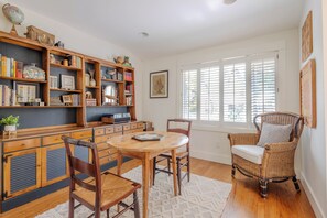 Une pièce comprenant une table à manger en bois, des chaises, une bibliothèque et un fauteuil en osier.