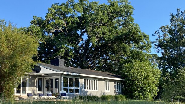 A house by a lake with a covered porch and large windows. - Lakefront home w/ Private Dock + Golf Cart l 8 min. to beach (St. Simons Island)