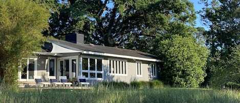 A house by a lake with a covered porch and large windows.