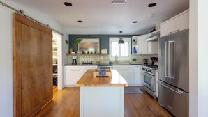 A modern kitchen with a wooden island, stainless steel appliances, and a view of the adjacent dining area. - Lakefront home w/ Private Dock + Golf Cart l 8 min. to beach (St. Simons Island)