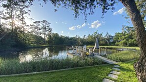 A serene lakeside park with a wooden dock, chairs, and a picnic table. - Lakefront home w/ Private Dock + Golf Cart l 8 min. to beach (St. Simons Island)
