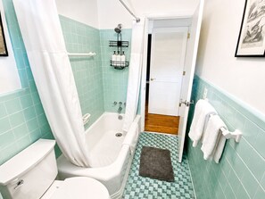 Une salle de bain avec une baignoire, des toilettes et un rideau de douche.
