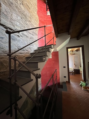 A staircase with metal railings leading to a room with a red accent wall.