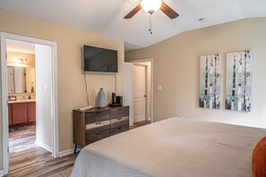 A bedroom with a large bed, a ceiling fan, a dresser, a TV, and two paintings on the wall. - Putt in the Pines 3BD 2 BA Charming Quiet Home (Aberdeen)