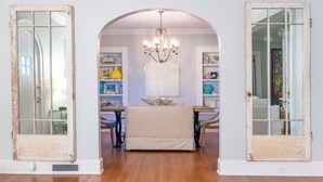 A room with an arched doorway, a chandelier, and a table with chairs. - Beautiful Bright 6 bedroom home in the heart of Buckhead (Atlanta)