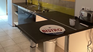 Moderni keittiö, jossa on musta työtaso, pesuallas, liesi ja roskakori.