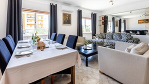 A dining area with a table set for four, a sofa, and a coffee table. - Cantinho da fraternidade - 3 bed apartment (Portimão)