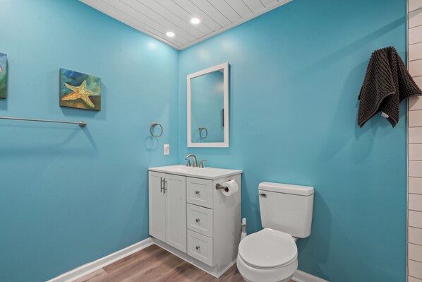 Een badkamer met een wit toilet, een wastafel met spiegel erboven en een handdoekrek met een handdoek.