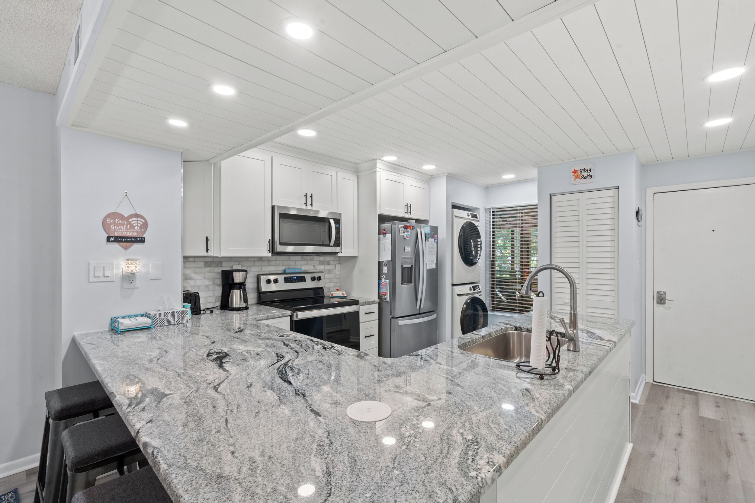 A modern kitchen with white cabinetry, stainless steel appliances, and a granite countertop.