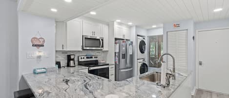 A modern kitchen with white cabinetry, stainless steel appliances, and a granite countertop.