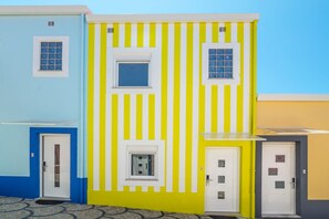 A building with a yellow and white striped facade, multiple doors, and windows. - House (Porto)