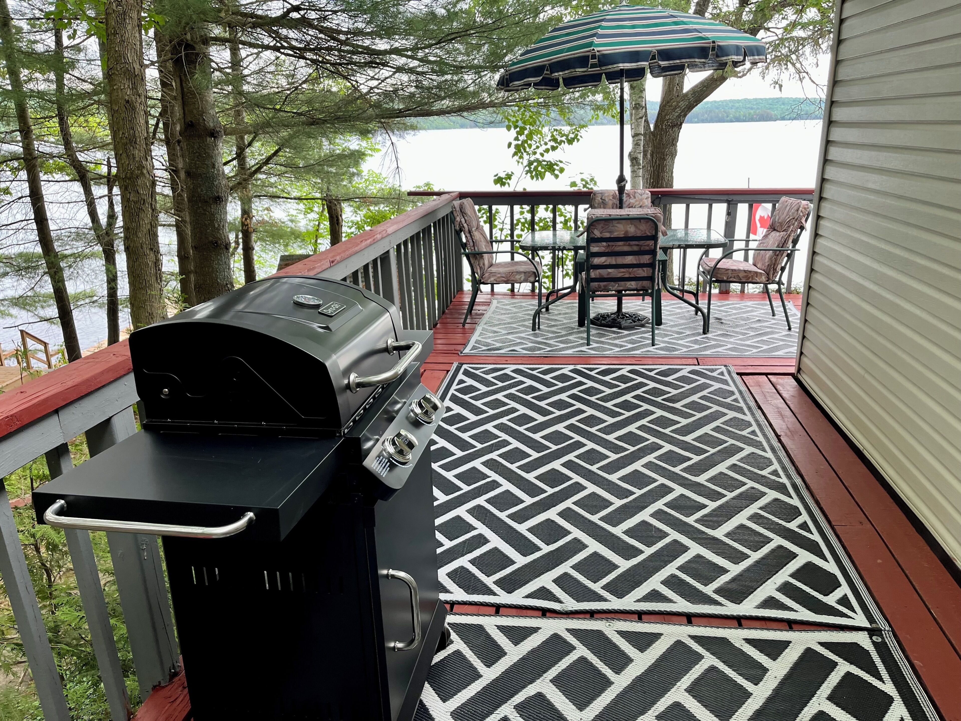 A deck with a grill, outdoor furniture, and a view of a lake.