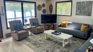 A living room with a sofa, armchairs, a coffee table, a TV, and decorative wall art.