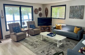 A living room with a sofa, armchairs, a coffee table, a TV, and decorative wall art.