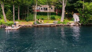 A lakeside cabin with a dock, surrounded by dense forest.