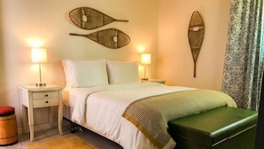 A neatly arranged bedroom with a bed, bedside tables, a bench, and decorative wall art.
